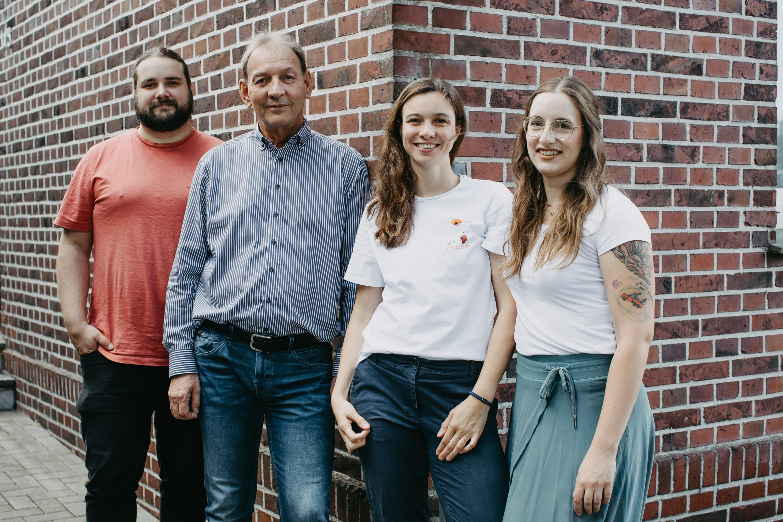 Vier Mitglieder des Support-Teams lehnen entspannt an einer Hauswand. Gemeinsam kümmern sie sich um den Anwendungssupport für unsere smartDach Kunden und stehen für kompetente Hilfe bereit.